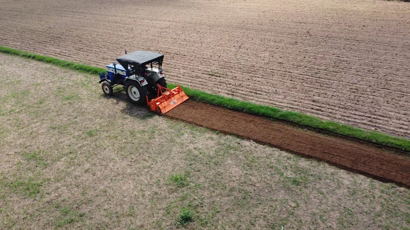A tractor-mounted rotavator preparing a field